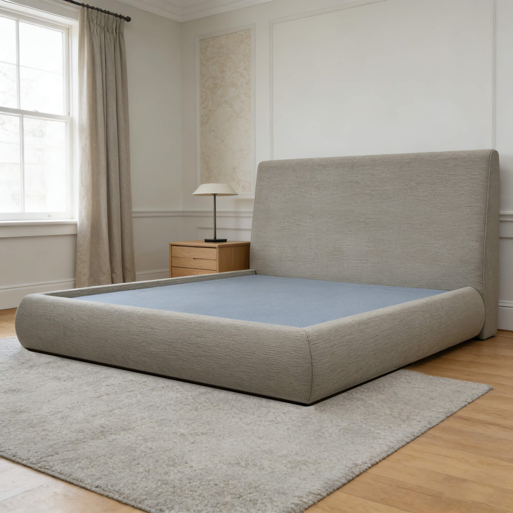 Front view of a minimalist grey fabric platform bed frame showing the recessed mattress system and wide cloud-like padded side rails