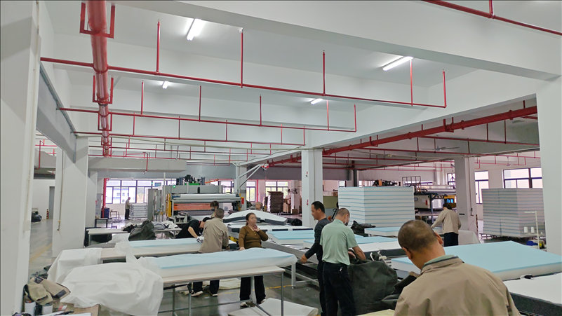 Professional workers assembling vacuum-compressed all-foam sofas at our China-based manufacturing facility, highlighting large-scale production capacity